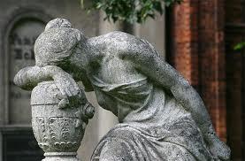 Thsi is a statue of a distressed woman draped over an urn, head in hand